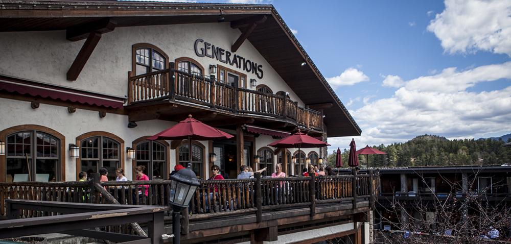 The Generations Tap & Grill restaurant from the outside with people sitting on a patio during the summer.