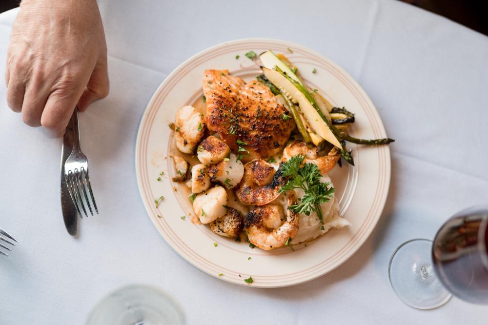 An aerial view of plated food and a hand reaching for a fork.