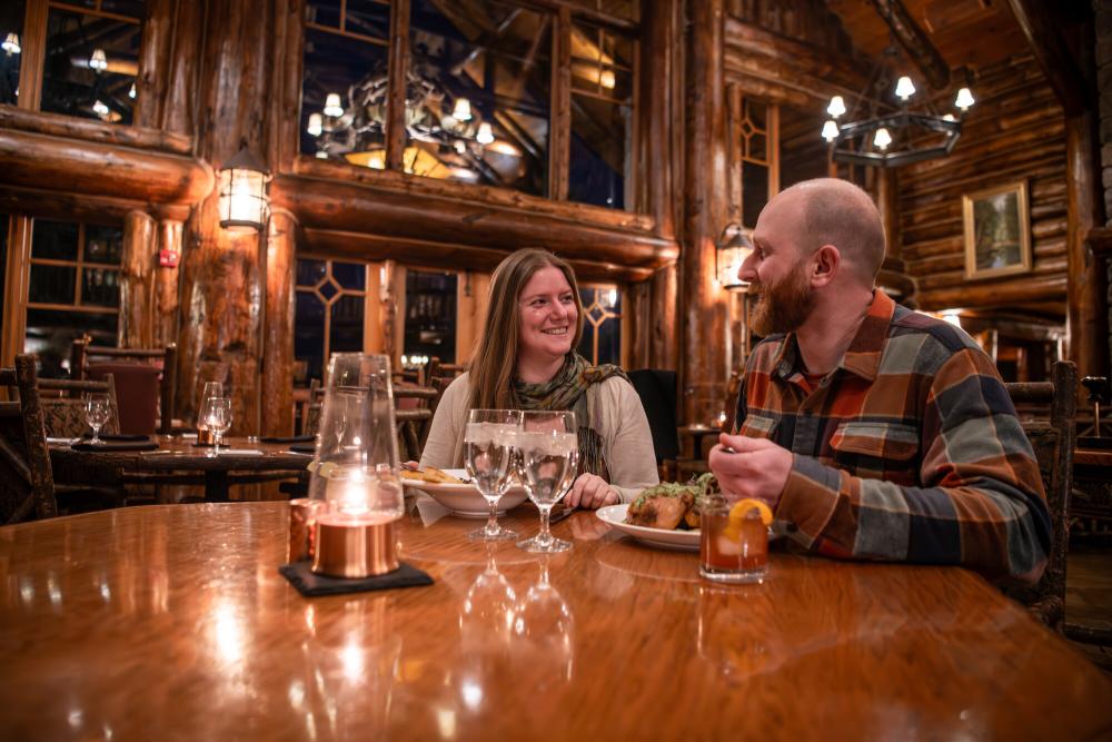 A couple dines in a grand lodge dining room.