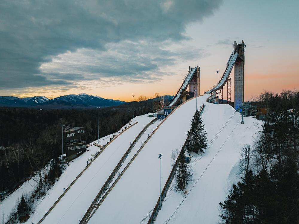 Two ski jumps tower over the trees in winter.