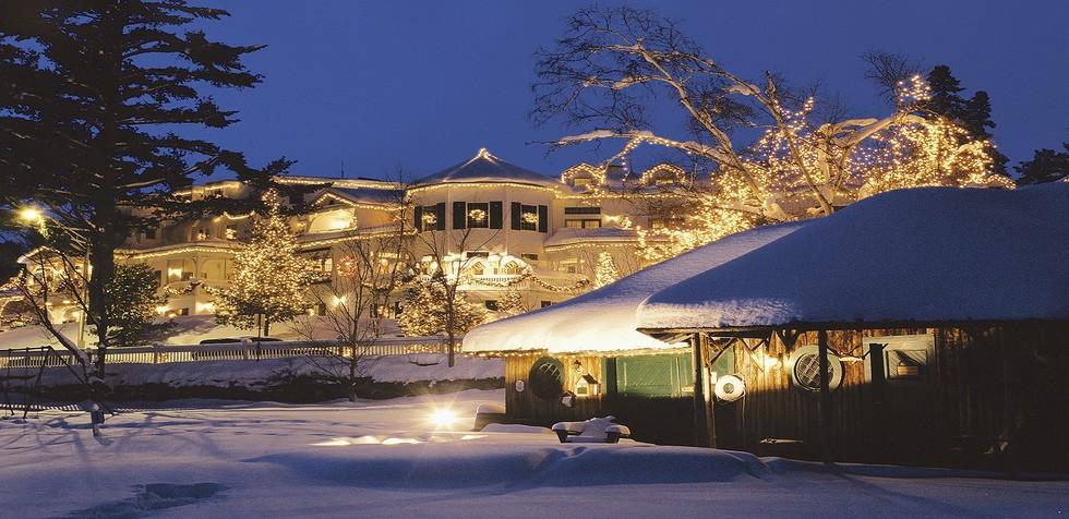 A winter scene of a vintage white hotel decorated for Christmas.