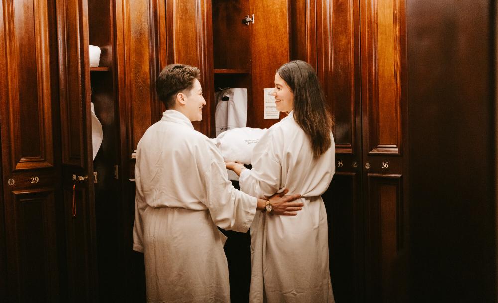 Two women wear robes at a spa.