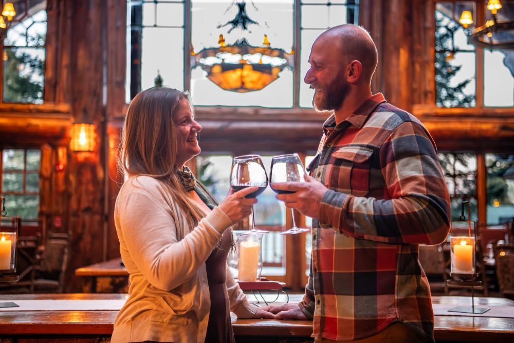 two people cheers drinks at a lodge.