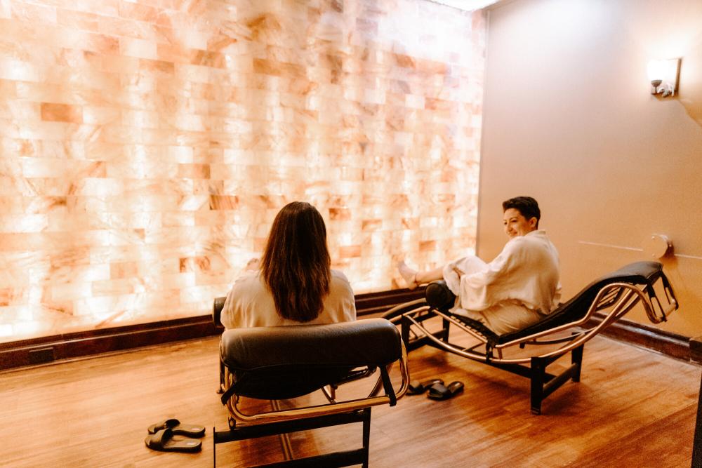 Two women enjoy a salt room in robes.