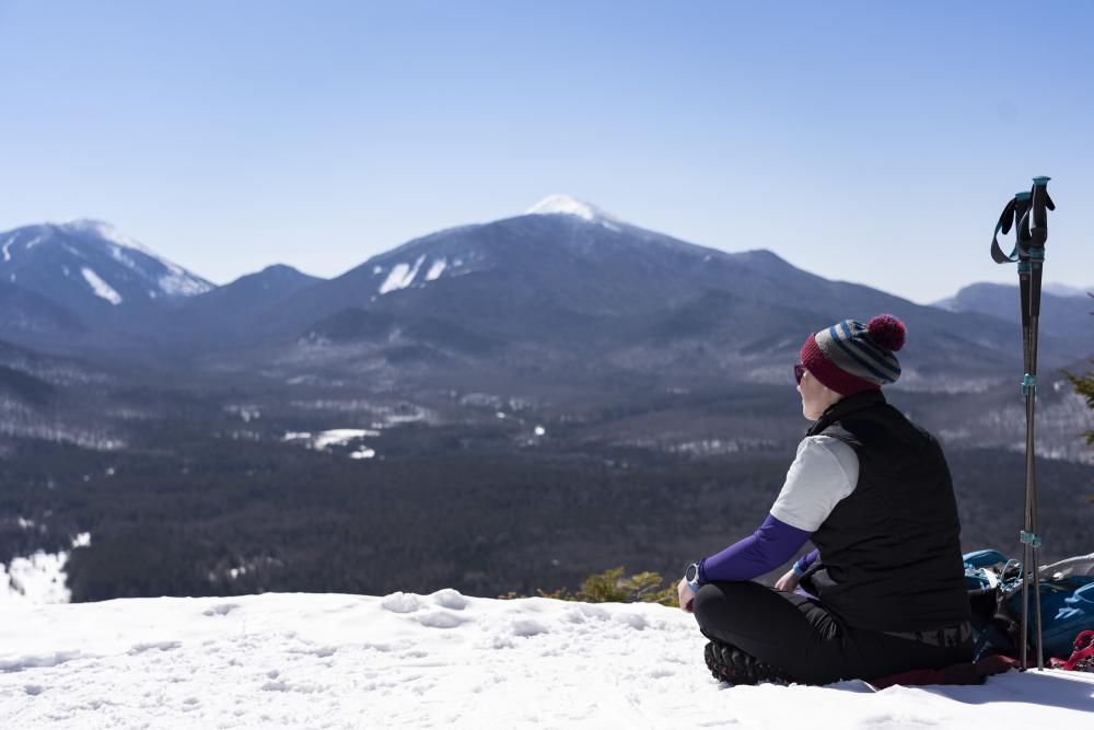 A hiker sits on Mt Van Hoevenberg's summit during the winter