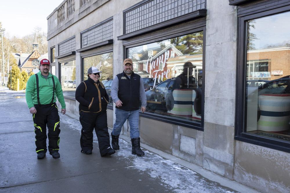 A group of snowmobilers walking in the town of Saranac Lake