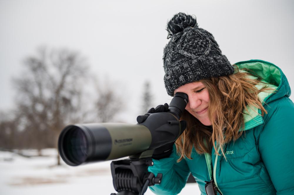 A birder looking through a spotting scope in the winter