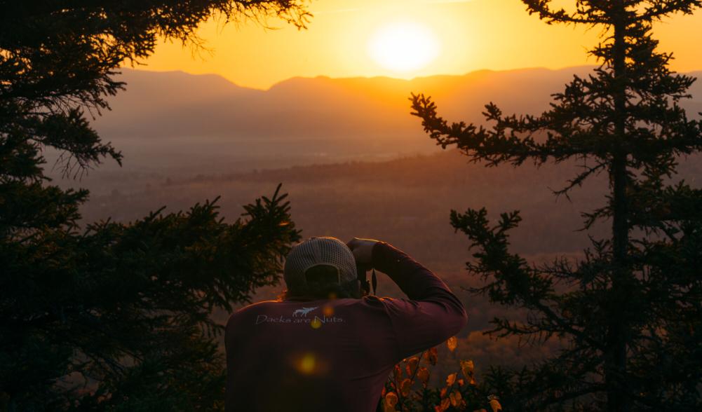 A man takes a picture of the sunset on an autumn day in the mountains.