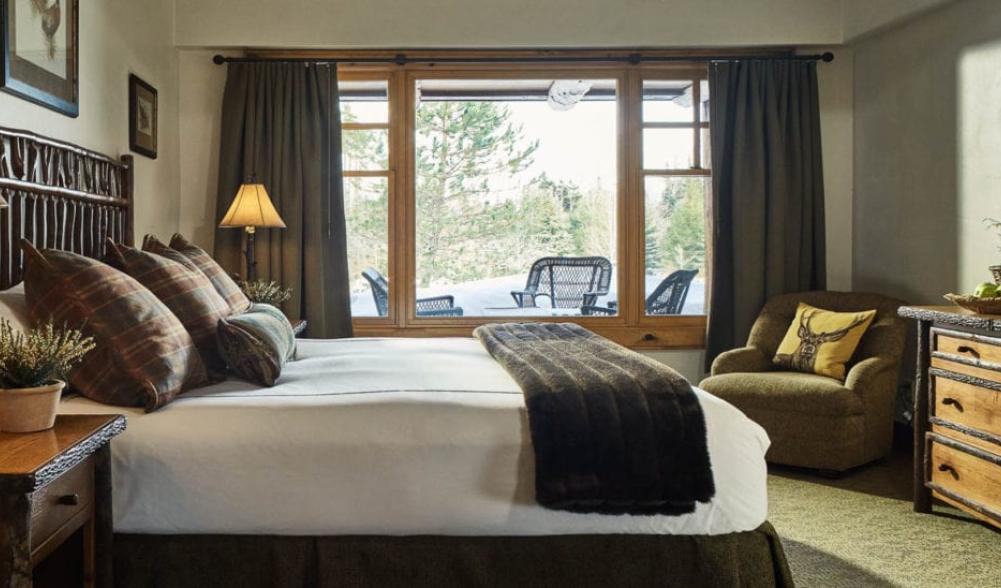 The interior of a guest room at a luxury mountain resort, featuring upscale rustic-inspired furnishings.