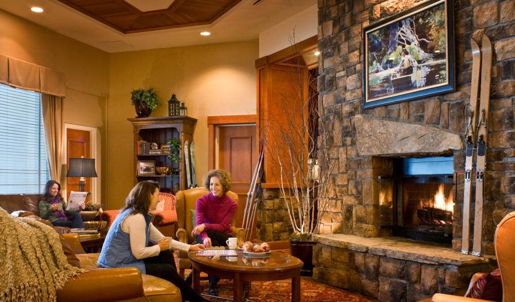 Two women chat in a hotel lounge next to a stone fireplace.