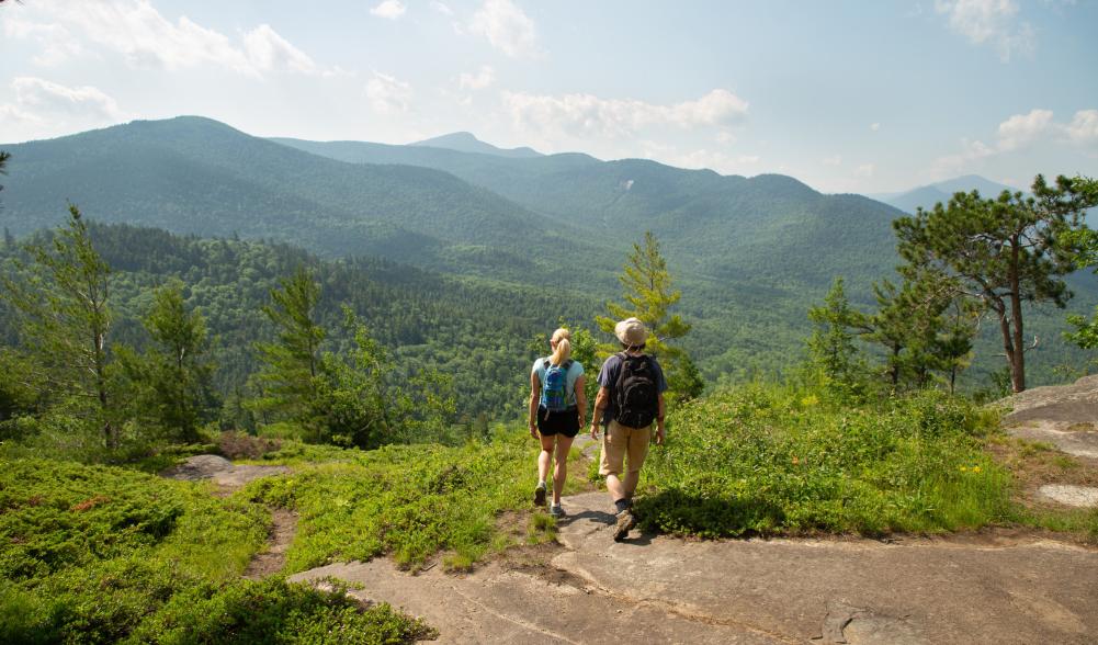 A couple looking out at the summit of Baxter Mountain in the summer.