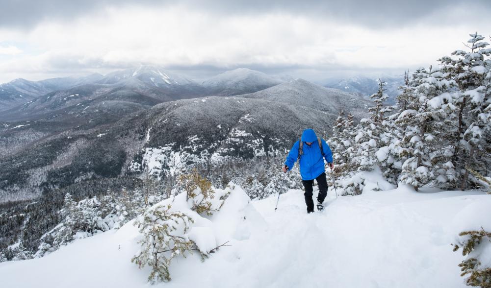 A person snowshoeing up a mountain in Keene Valley during the winter.