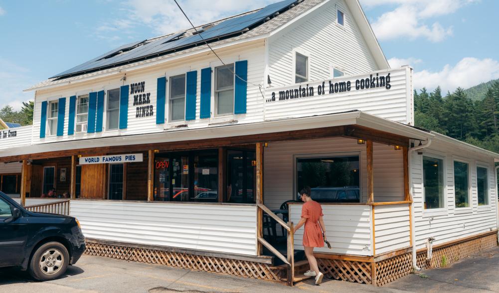 A woman walking into Noon Mark Diner during the summer.