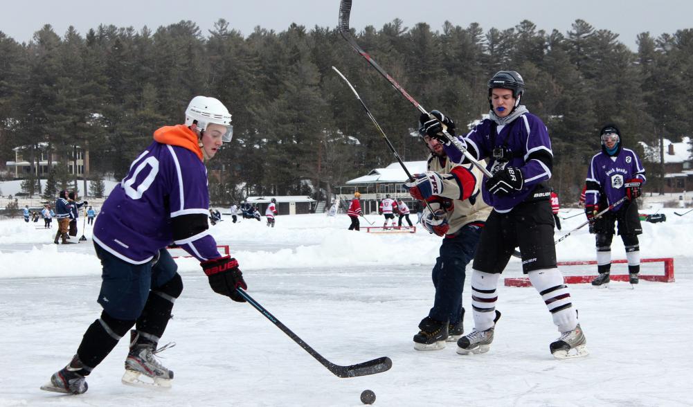 A pond hockey tournament fills several small rinks on a frozen lake.