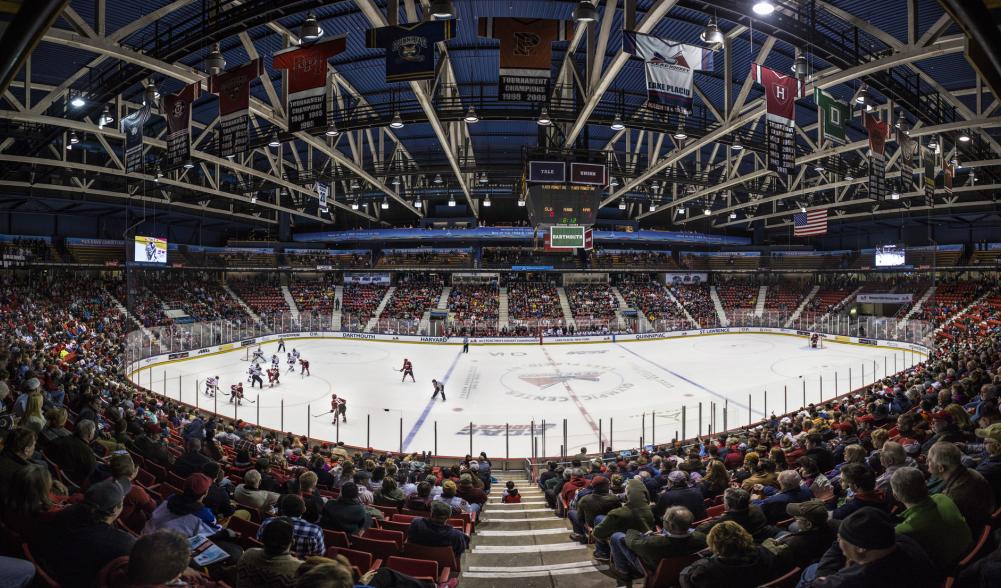 A wide-angle view of a hockey arena. Fans fill the stands and watch a game.