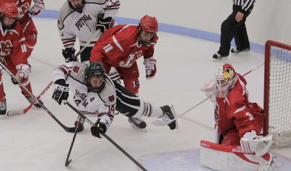 Collegiate hockey players scramble in front of the net.