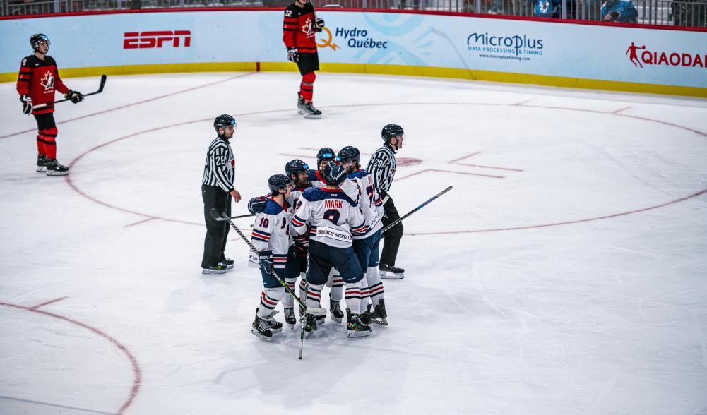 A cluster of hockey players cluster together in celebration on the ice.