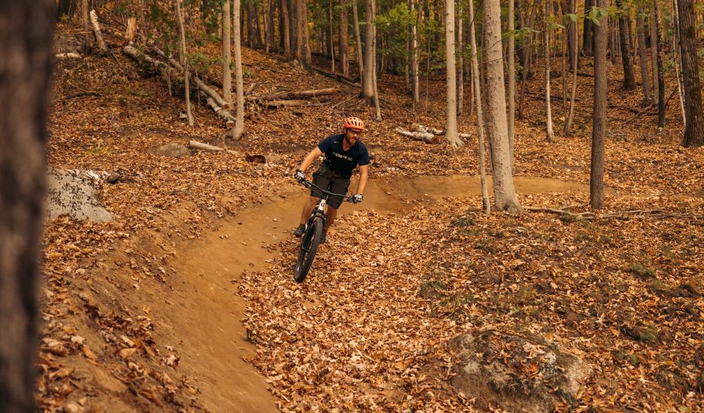 Mountain bikers rides leaf-covered trail