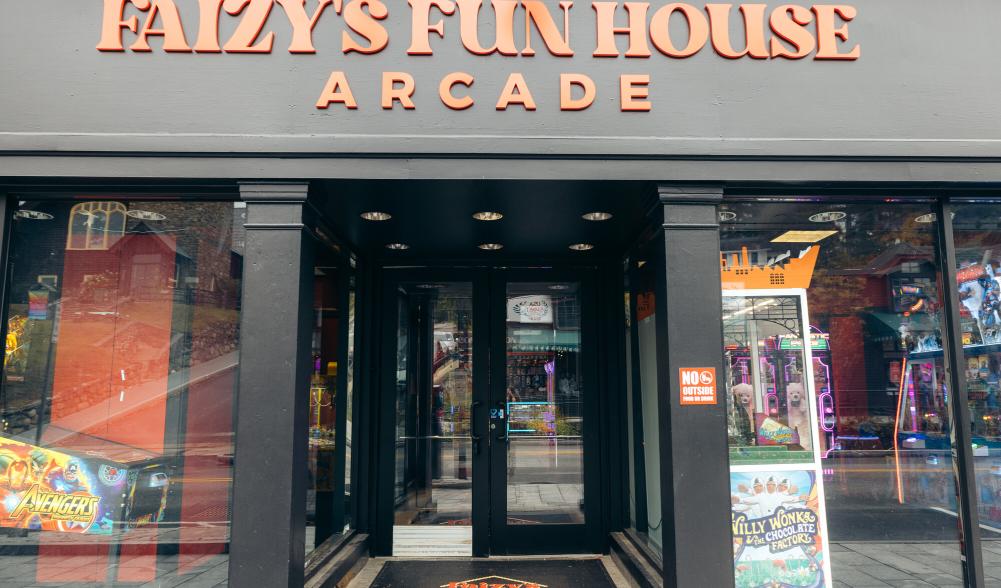 The exterior of an arcade with large glass windows. The building reads, "Faizy's Fun House Arcade"