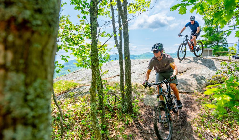 A couple mountain bikers leaving a rocky cliff