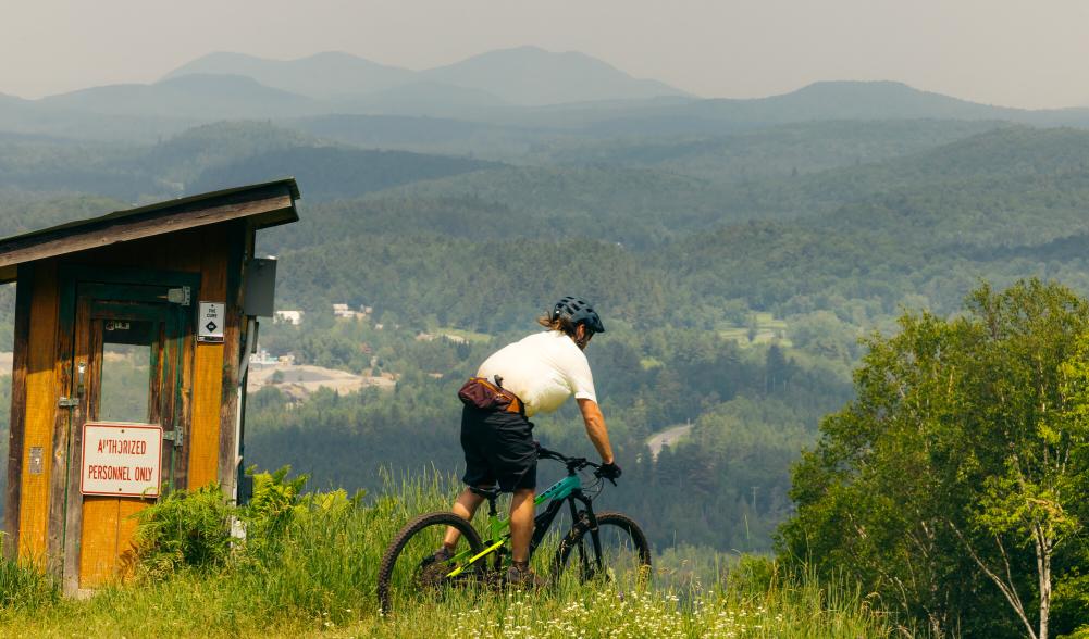 A mountain biker on top of a ski hill trail