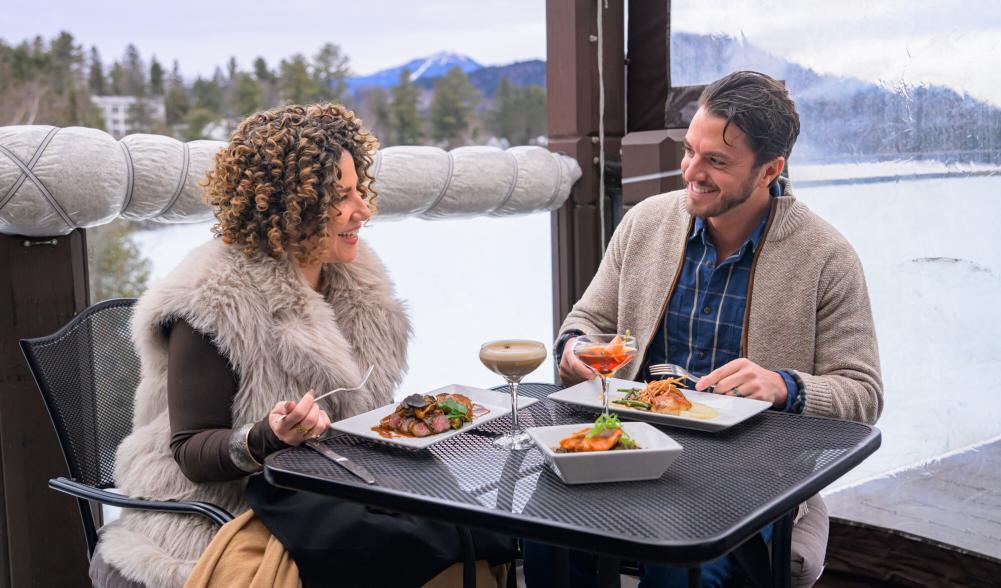 Man and woman dine on outdoor deck in winter