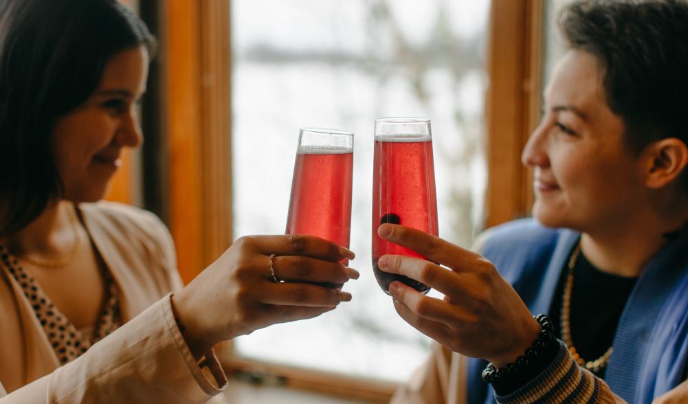 Two women cheers pink mimosas