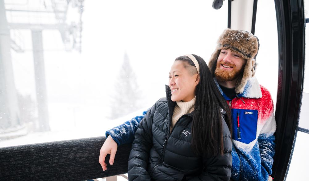 Woman leans against man riding in glass gondola