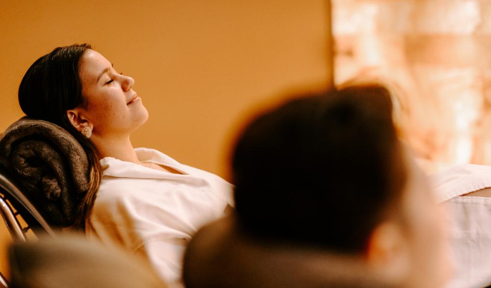 Two women relax in lounge chairs in spa robes