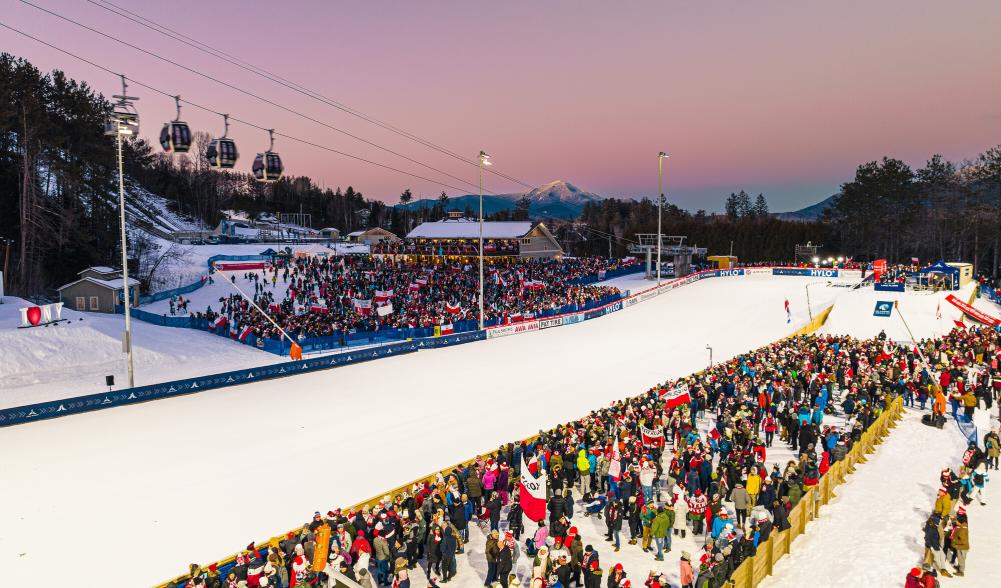 Crowd gathered at base of ski jumps at sunset