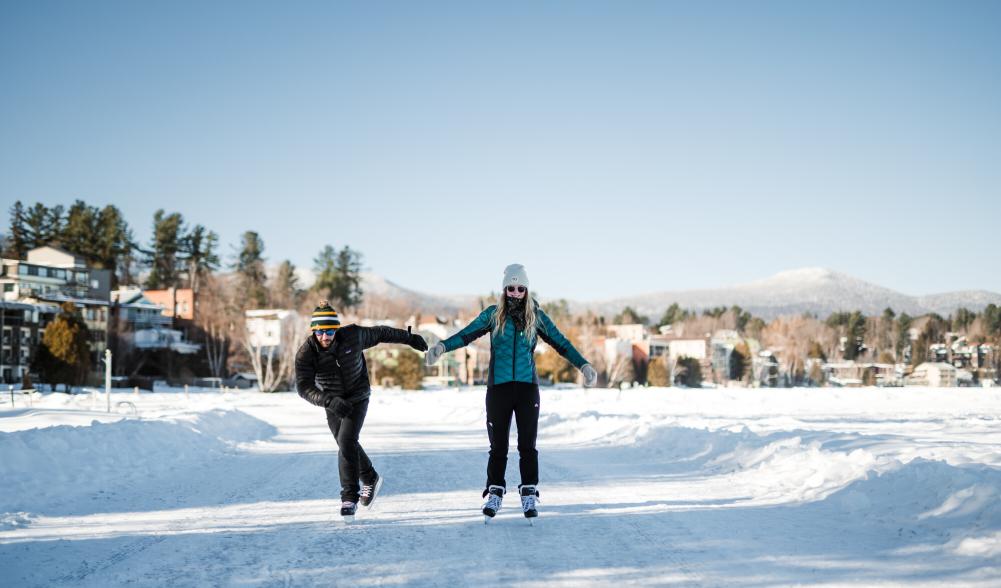 Man and woman ice skate on frozen lake