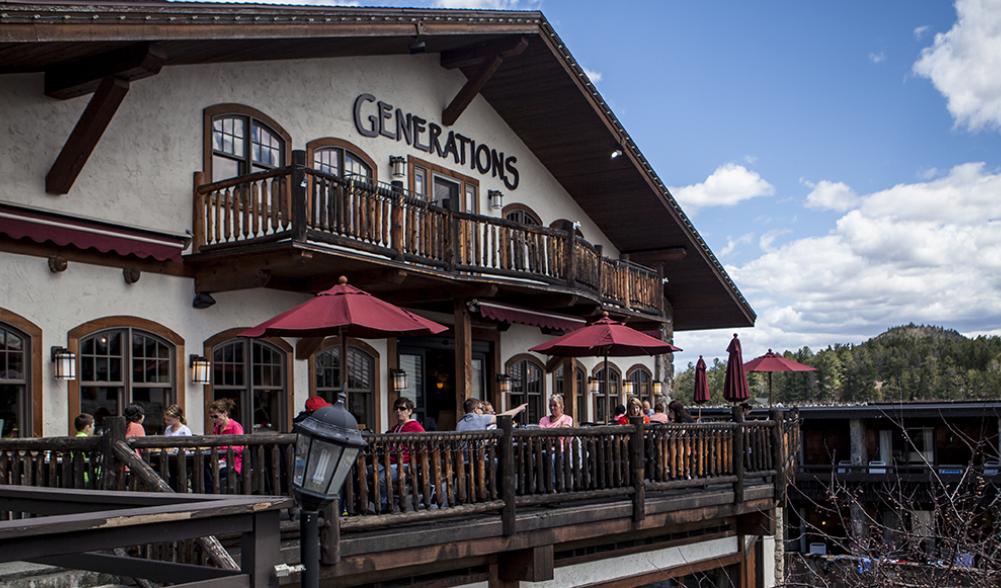 The Generations Tap & Grill restaurant from the outside with people sitting on a patio during the summer.