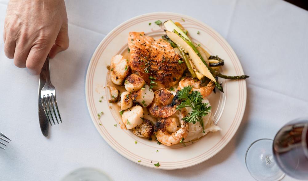 An aerial view of plated food and a hand reaching for a fork.