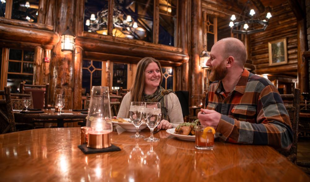 A couple dines in a grand lodge dining room.