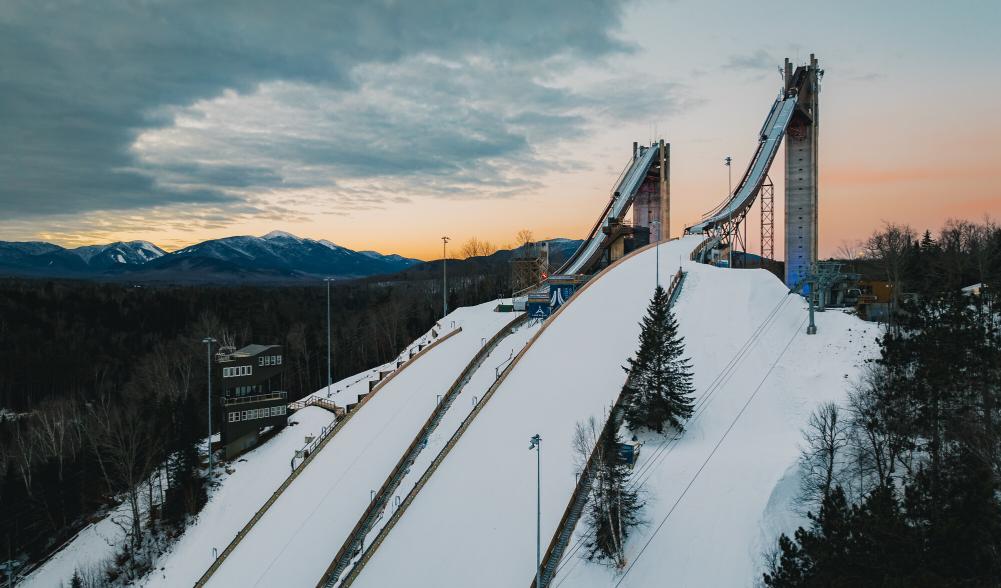 Two ski jumps tower over the trees in winter.