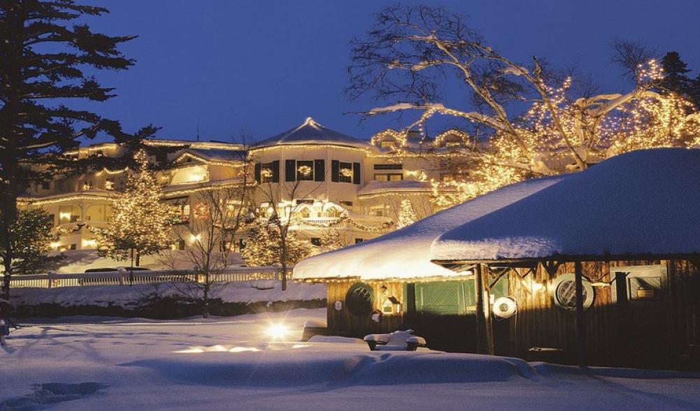 A winter scene of a vintage white hotel decorated for Christmas.