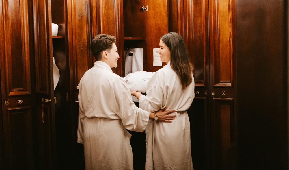 Two women wear robes at a spa.