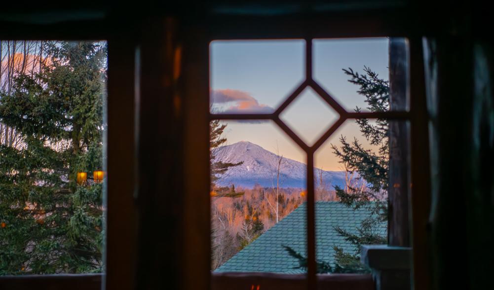 A look at a mountain from a snowy window.