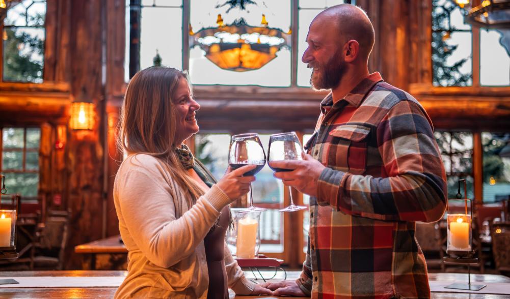 two people cheers drinks at a lodge.