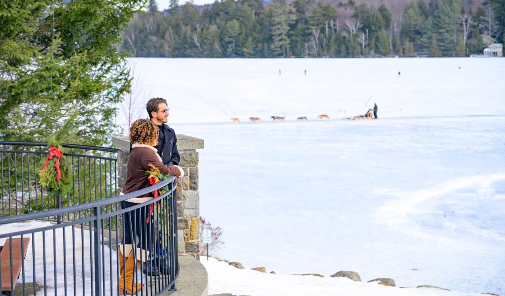 A man and woman look out at the lake from a balcony.