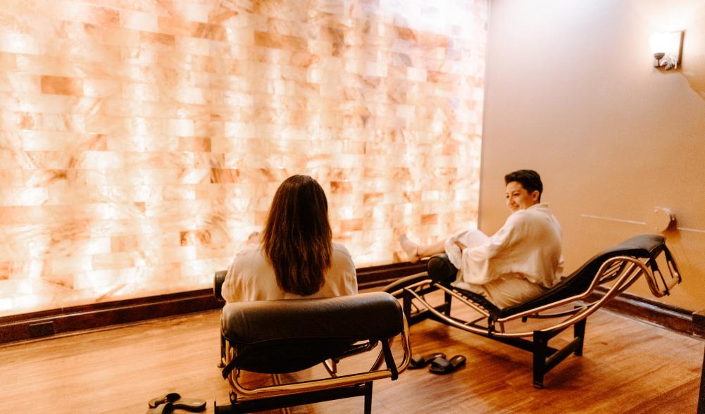 Two women enjoy a salt room in robes.