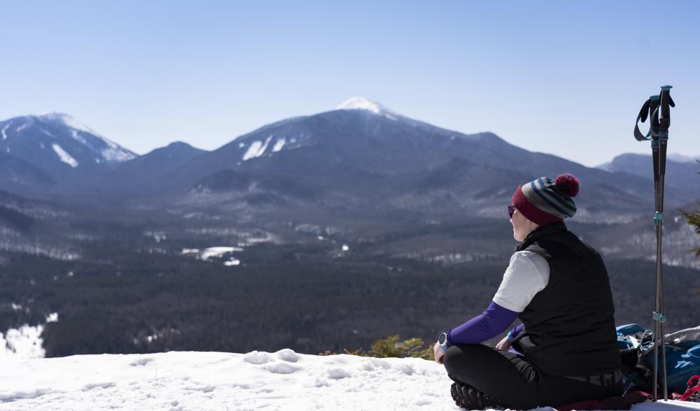 A hiker sits on Mt Van Hoevenberg's summit during the winter