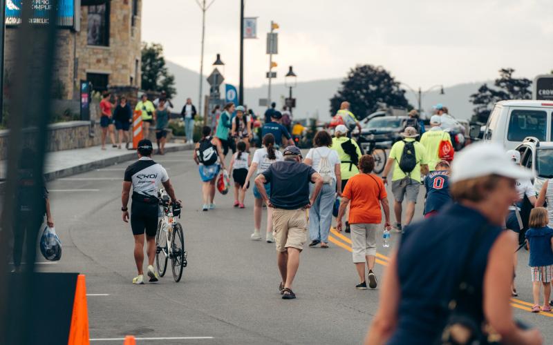 Athletes and spectators walk on road in Lake Placid during Ironman