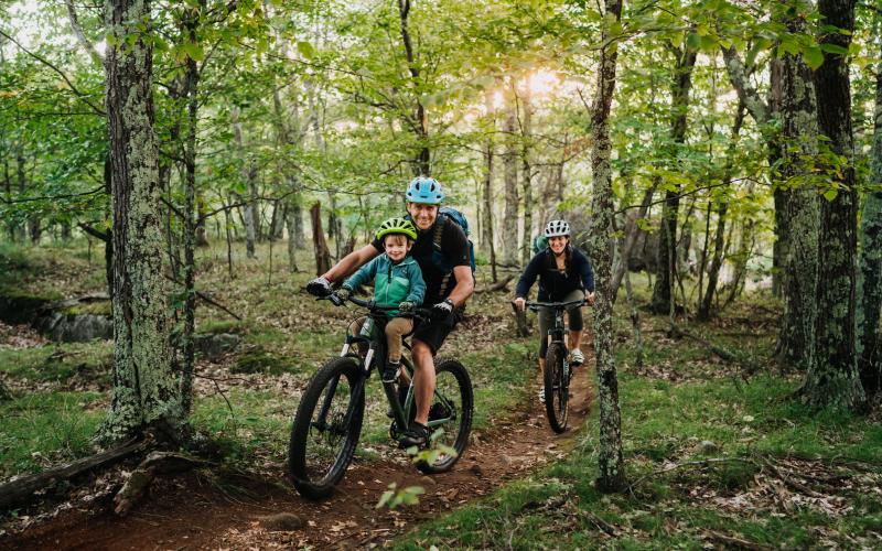 Family riding through the woods, with a little one strapped to a parent.