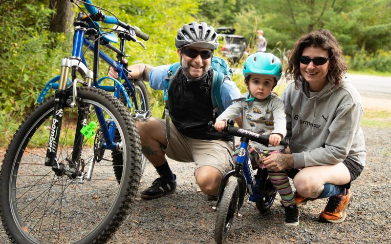 Smiling young family with toddler kick bike