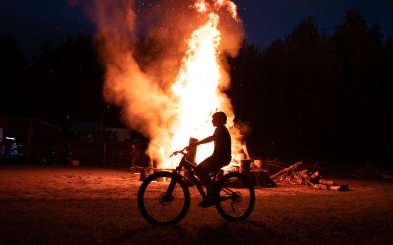 Bicyclist rides past a big bonfire