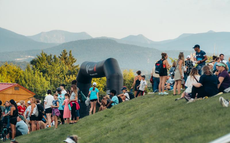 Spectators on hill above Ironman finish with mountains in background