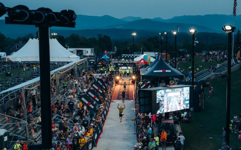 Ironman athletes approach finish after dark with faint mountains in distance