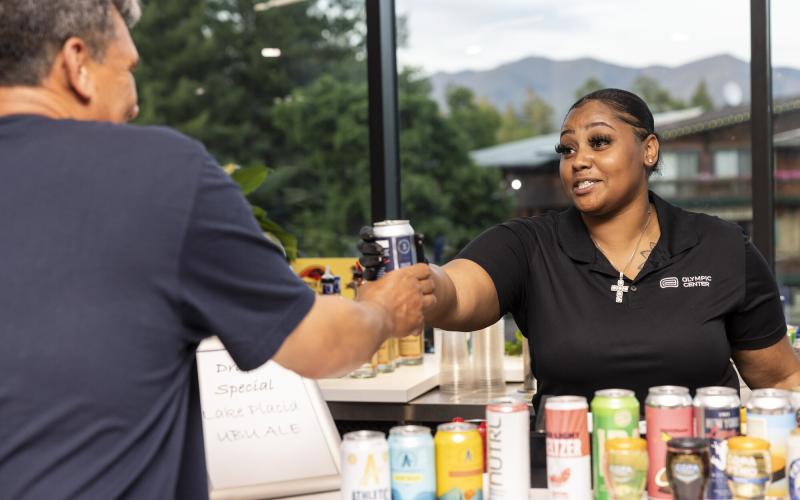 Friendly bartender hands a drink to a patron