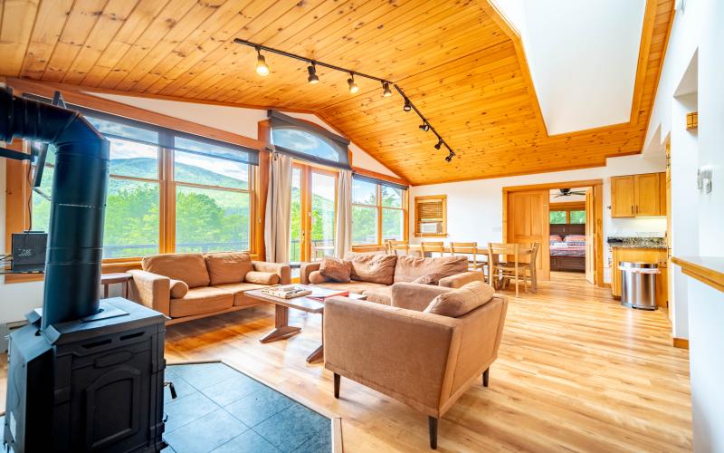 Interior Great Room with comfy couches, a wood stove and knotty pine paneling throughout